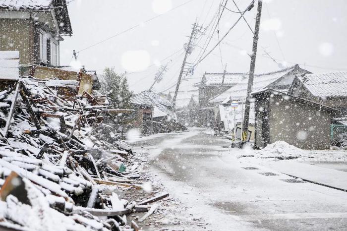 1月13日，日本石川县，火山在1月1日发生强震后，日本积雪覆盖着倒塌房屋。地震图/视觉中国