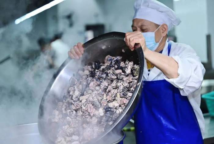 （后厨师傅将乌骨鸡下锅熬汤，受访者供图）