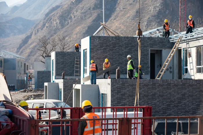 2024年1月4日，门头沟区斋堂镇沿河口村异地安置项目建设现场，建筑工人正在拼装房屋。