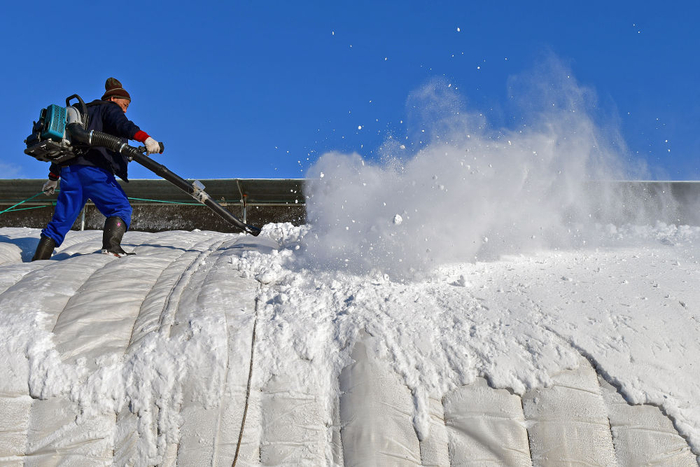 2023年12月17日，农民在山东省烟台市福山区门楼街道用鼓风机清理暖棚上的积雪。新华社发（孙文潭摄）