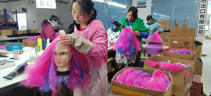 假发厂内工人为假发修理定型.