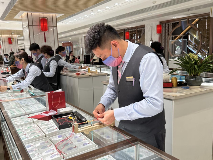 图为工作人员正在编转运珠红绳手链。