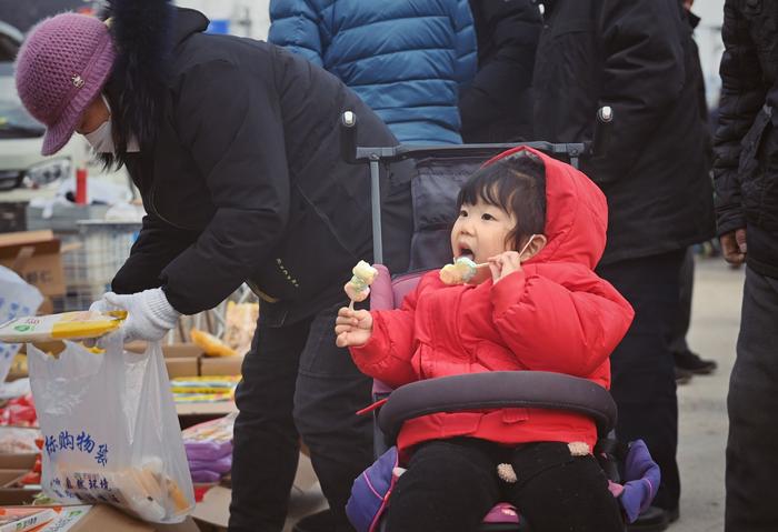 2月1日，平谷区靠山集大集上，一个小女孩正在吃棒棒糖。新京报记者 薛珺 摄