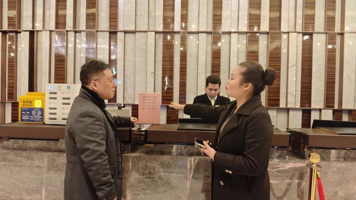 图为永恒朗悦酒店房务总监韦献妙（右）向记者介绍酒店明码标价情况。