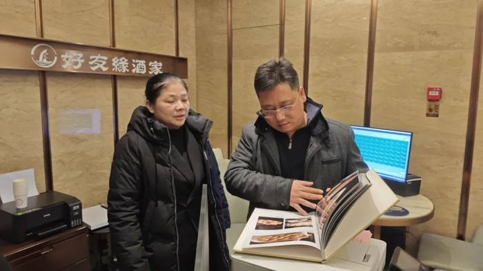 图为好友缘酒家西大店餐饮经理邓建欧（左）向记者介绍餐厅菜谱及标价情况。