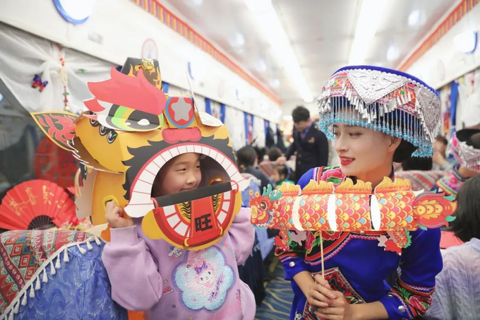 一名小乘客收到乘务员送上的龙元素装饰品。图源：“中国铁路”微信公众号