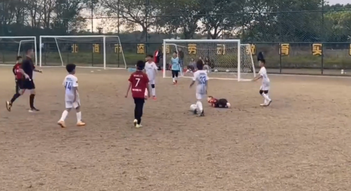 一名小球员在比赛中被踢倒在地。 视频截图