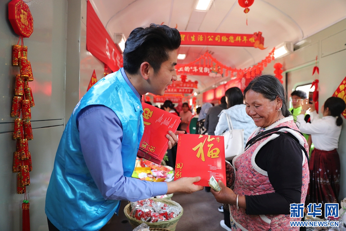2月2日，“慢火车”年货街上，列车工作人员为乘客送福字。图源：新华网（杨紫轩 摄）