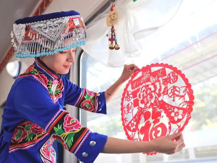 乘务员在车厢内贴上窗花，营造喜庆的节日氛围。图源：“中国铁路”微信公众号