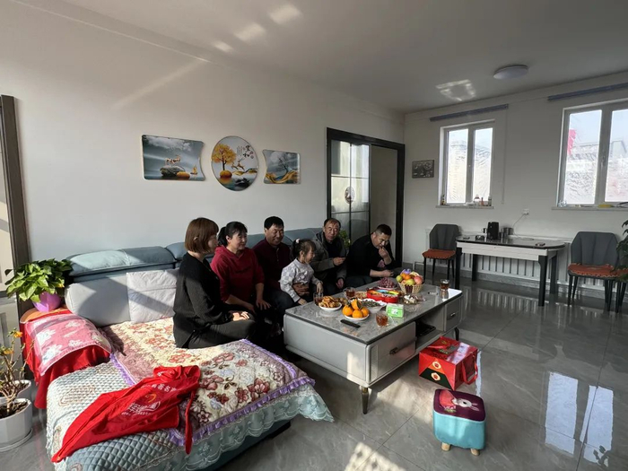 ▲王牛的旧房只有40平方米，进门就是床。搬到新家后他有了宽敞的客厅，和家人一起过新年。新京报记者 乔迟 摄