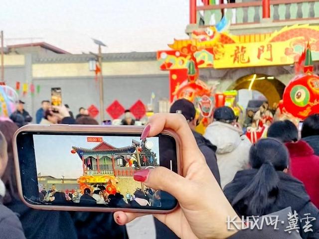 游客正在用手机记录村里的民俗表演。长城网·冀云客户端记者 高航 摄