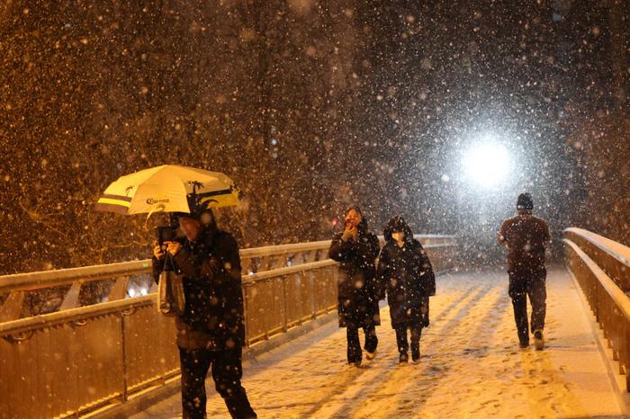 2月20日，北京市东直门南大街过街天桥，市民在雪中行走。新京报记者 王贵彬 摄