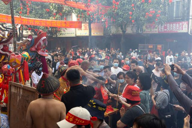 2月20日，广西宾阳县，人们聚集在香炉台旁，火祭司正在为前来上香的群众戴上“开光丝巾”，传递节日祝福。江畅/摄