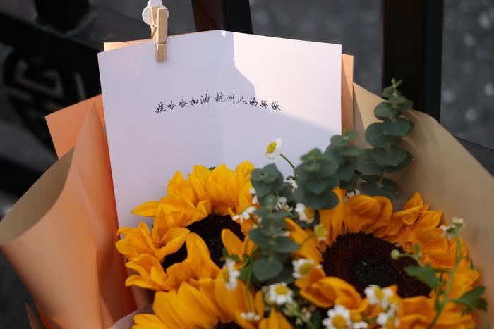 一束向日葵的卡片上写道：娃哈哈加油，杭州人的骄傲。