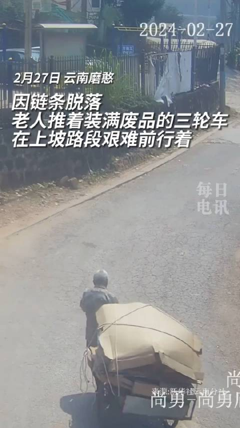 因链条脱落老人推着装满废品的三轮车在上坡路段艰难前行着