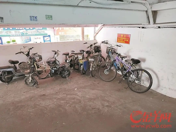 城中村一公寓，消防通道拐角处电动自行车随意停放，而墙上贴着“公共消防通道出入口禁止停放一切车辆”的告示