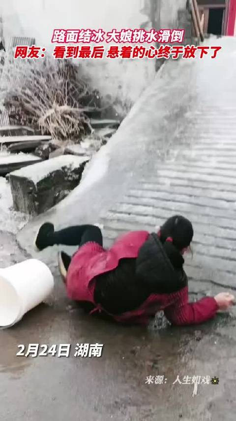 路面结冰大娘挑水滑倒严重怀疑这冰就是这样撒出来冻上的