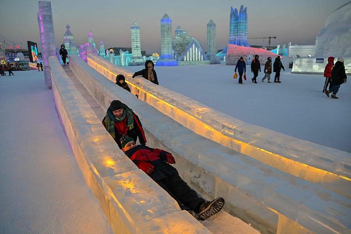 人们在哈尔滨冰雪大世界的冰道上滑行。