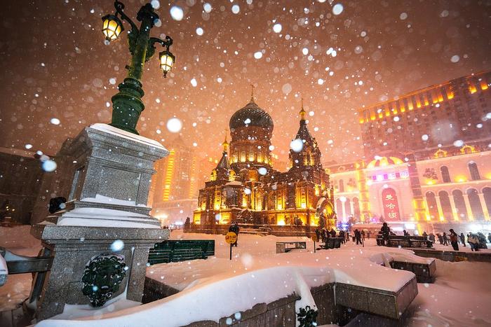 游人在哈尔滨索菲亚教堂广场欣赏雪景。