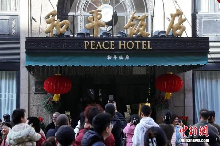 游客在和平饭店门前拍照留念。中新网记者 汤彦俊 摄