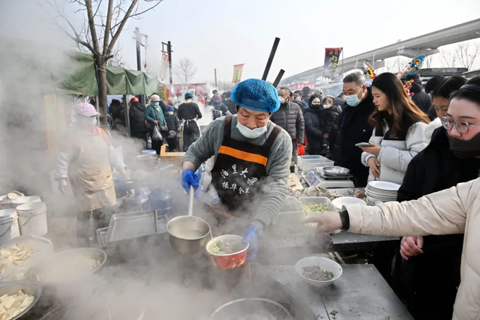 人们在泊里大集上选购风味小吃 李紫恒 摄