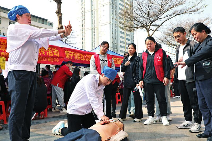 南宁市第四人民医院志愿者向群众传授急救知识，并示范急救手法。（温静 摄）