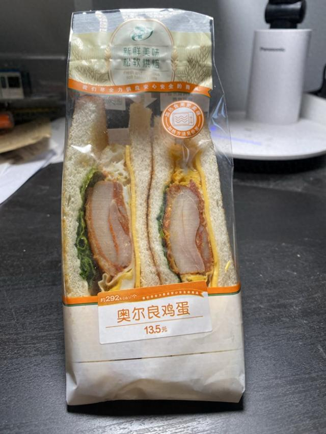奥尔良鸡蛋三明治外卖单上显示为14.2元，而包装上标注的价格是13.5元，外卖贵了7毛钱。 受访者 供图