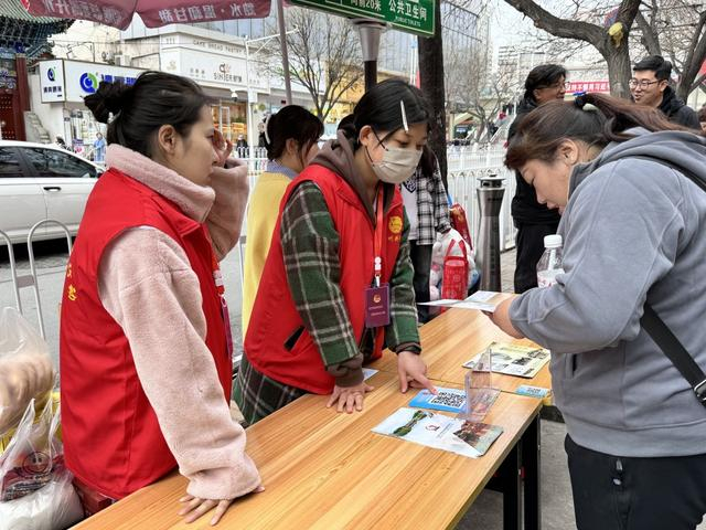 在天水市秦州区的街道一侧，志愿者为前来品尝天水麻辣烫的外地游客答疑解惑。新华社记者 文静 摄