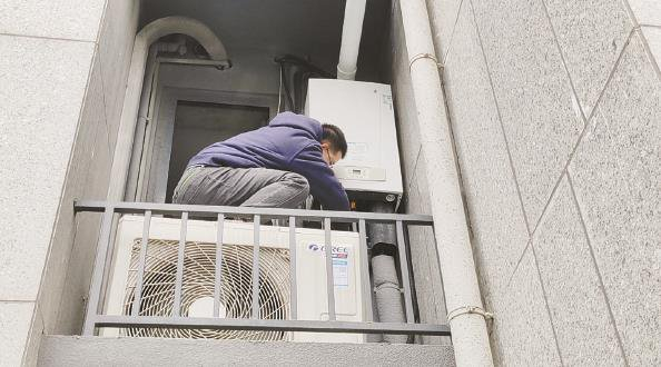             有业主称，日常调试壁挂炉需踩在空调外机上才能够到阀门  王军  摄          