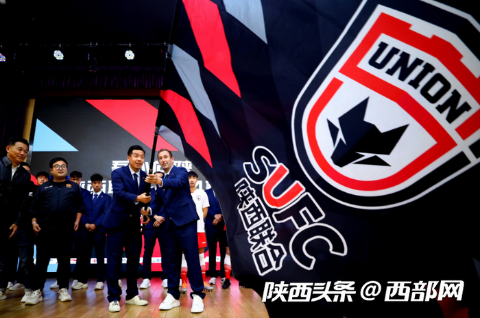 西班牙籍主教练奥斯卡和球队队长丁捷挥动俱乐部队旗。