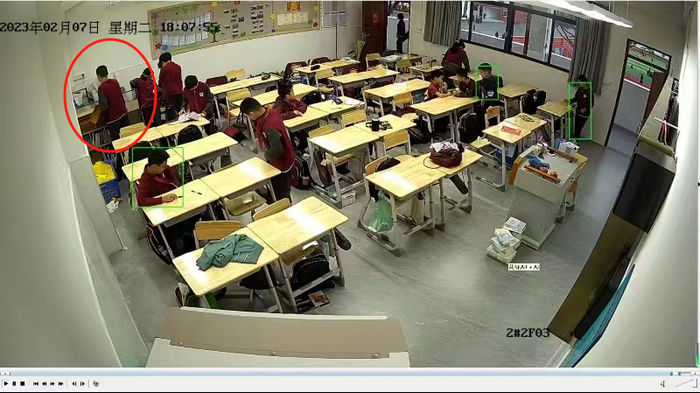 监控画面显示，2023年2月7日18时07分许，小付（图中红圈内的男生）将日记本放在班主任刘女士的桌上。 受访者供图