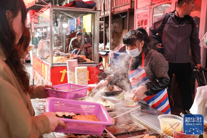 ▲在天水市秦州区的一条小吃街，一个麻辣烫摊位的摊主在制作麻辣烫。（图片来源：新华社）