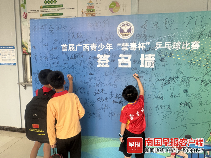 选手和观众在"禁毒杯"签名墙签名.