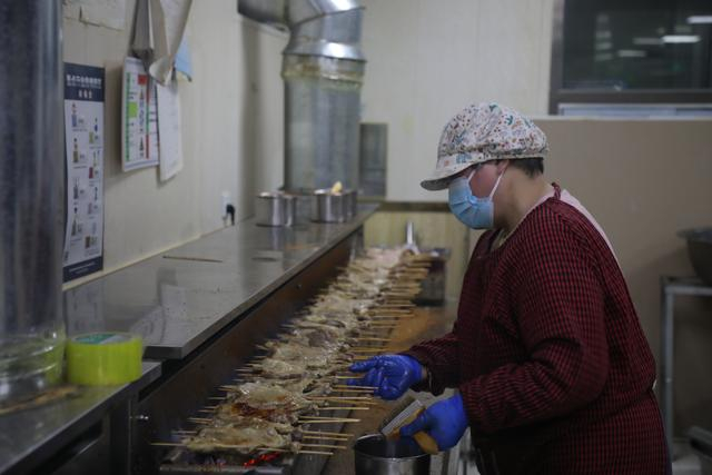 “鹅腿阿姨”陈秀凤在店铺内烤制鹅腿。张南宁摄