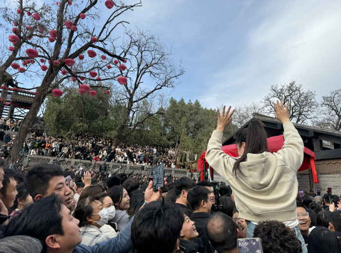 ▲为了吸引王婆注意，有人骑在朋友的脖子上，一下高出来半个身子，挥舞着双臂大喊。新京报记者 乔迟 摄