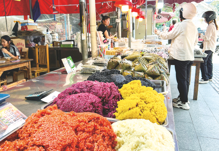     市民在市场选购五色糯米饭等当季美食。    本报记者潘浩 摄