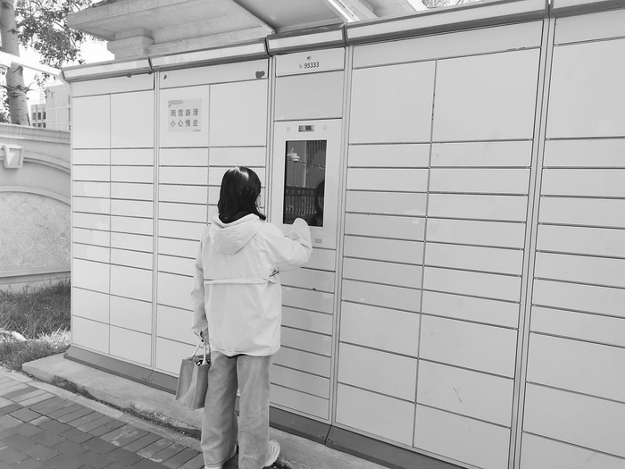 图为快递员把包裹送到客户手中.图为快递员在小区里用推车挨家送包裹.