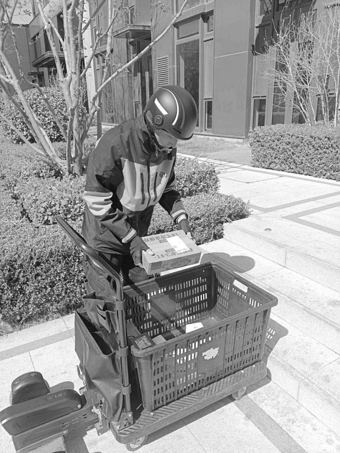 图为快递员在小区里用推车挨家送包裹.图为快递员把包裹送到客户手中.