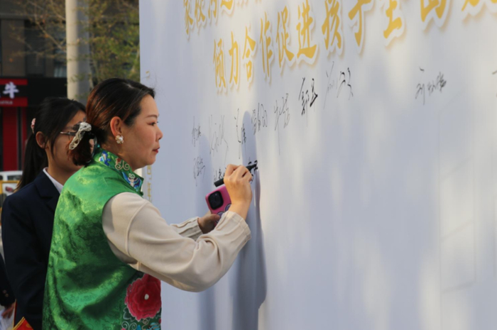 早上七点,家长们陆续在校门口签到步入校园,先在签名墙签名留念,后到