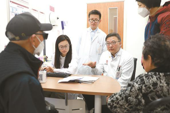             王坚医生（右一）在为帕金森病患者诊疗          