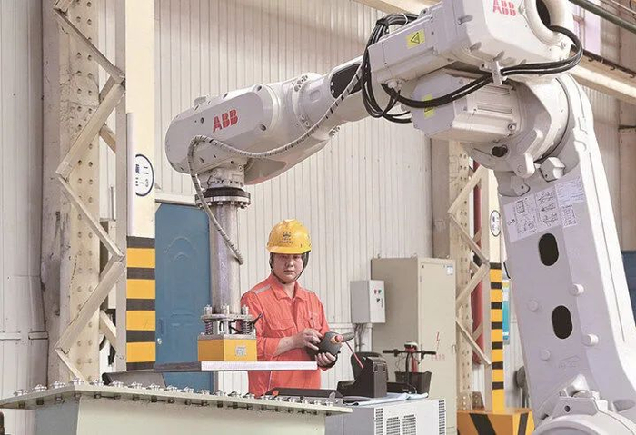 技术人员在高速道岔垫板智能生产线上调试机器人。