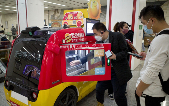 2023年3月29日，北京地铁6号线朝阳门站，一名乘客正从无人餐车中取出早餐。新京报记者 王贵彬 摄