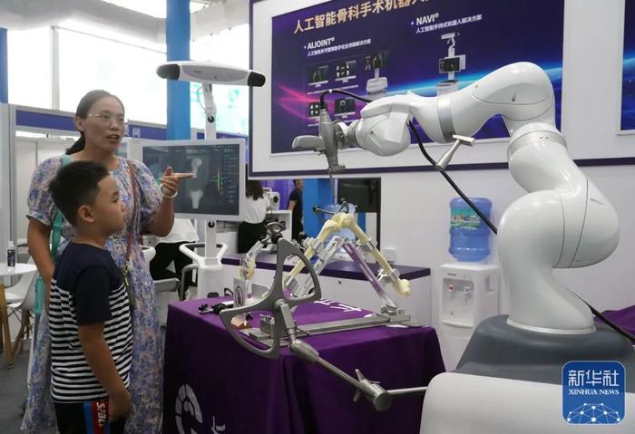 学生在参观了解人工智能骨科手术机器人。图片来源：新华社（记者：任超）<p cms-style=