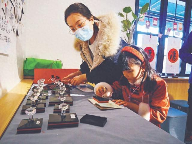 北京中轴线主题文创店内，家长与孩子正在盖章中轴线的十三处建筑印章。中青报·中青网见习记者 谭思静/摄