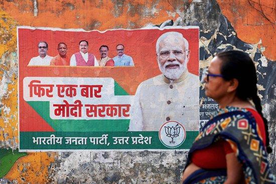     当地时间2024年3月24日，印度瓦拉纳西，在即将举行的大选之前，一名妇女从印度总理莫迪的竞选海报前经过。视觉中国供图