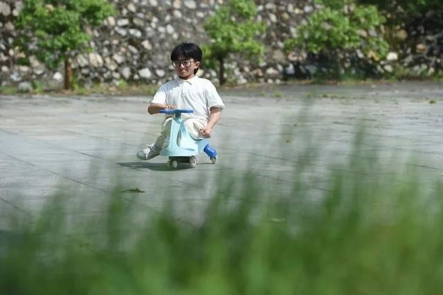 张亮驾着扭扭车在校园里 新华社记者 周牧 摄