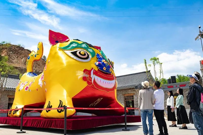 　　▲游人在晋中左权县桐峪1941小镇观赏取名为“太行虎娃”的世界最大布老虎