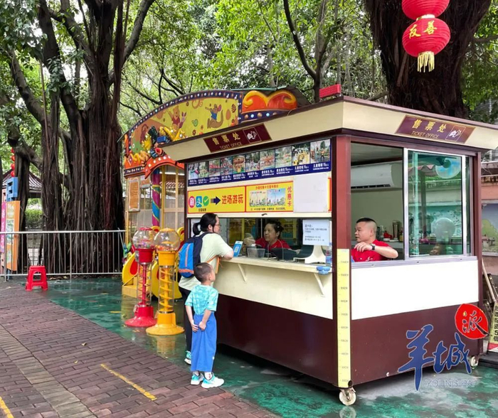 有家长带着孩子到售票亭买票