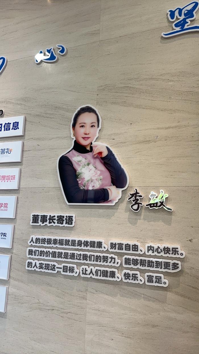 日赢控股办公楼一楼的宣传墙显示李敏为公司董事长