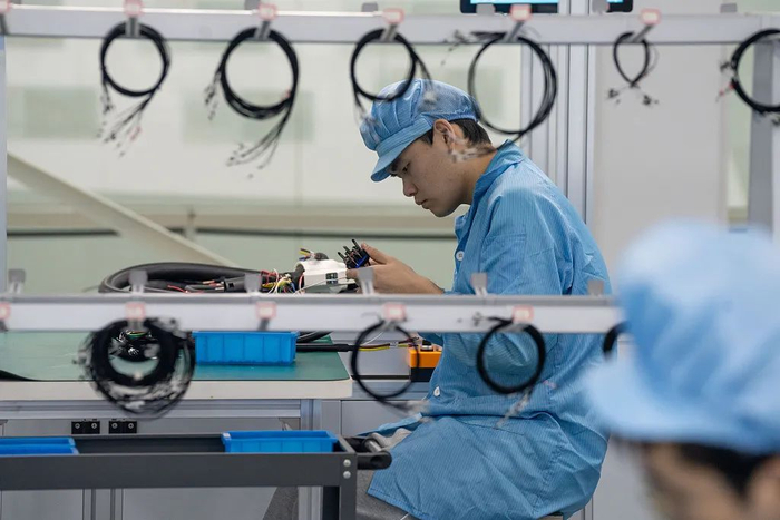 肥东县合肥循环经济示范园内一车间内，技术人员们在梳理电动汽车充电桩插头线束。（视觉中国）